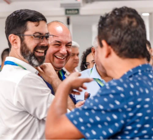 Foto de três participantes do seminário interagindo em um momento descontraído