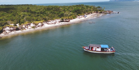 Barco de pesca, no mar, com praia ao fundo