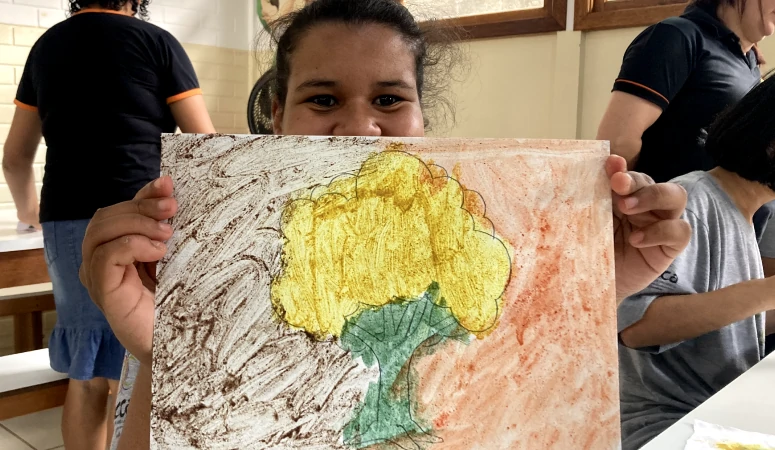 Aluna da APAE exibindo seu desenho de uma árvore